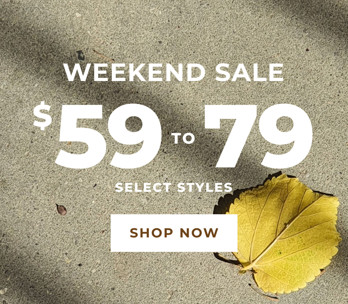 Promotional graphic for a weekend sale showing large white text reading 'WEEKEND SALE', '$59 TO $79', 'SELECT STYLES', and a 'SHOP NOW' button over a textured gray background with a yellow leaf in the lower right corner.